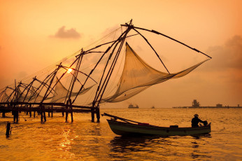Der Himmel leuchtet golden wie die Sonnenuntergänge und wirft den Schatten von Cochins chinesischen Fischernetzen und Booten in Kerala.
