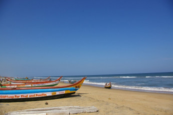 Das Wasser schäumt am feinen gelben Sand des Marina Beach, dem belebtesten Strand von Chennai mit Fischern und Touristen.