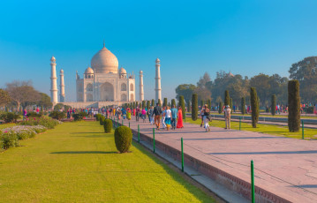 Besucher spazieren durch die wunderschönen Gärten zum weltberühmten Taj Mahal in Agra. Dieses Mausoleum aus elfenbeinweißem Marmor wurde 1983 zum UNESCO-Weltkulturerbe erklärt. - Foto von muratart