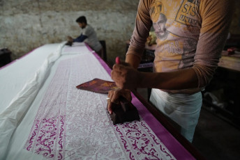 Der Blockdruck auf Stoffen ist eine alte Tradition in Rajasthan. Hier arbeiten Handwerkskünstler in einer Textilfärberei an einem langen Stück Stoff - Foto von  Wang Sing