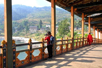 Ein Tourist fotografiert den Punakha Dzong in Bhutan vom Puna Mocchu Bazam aus. Als das Kloster im 17. Jahrhundert errichtet wurde, erbaute man eine Holzbrücke über den Mo Chhu-Fluss. Diese wurde jedoch 1957 von einer Sturzflut weggespült und durch eine schöne freitragende Brücke im traditionellen Stil ersetzt.