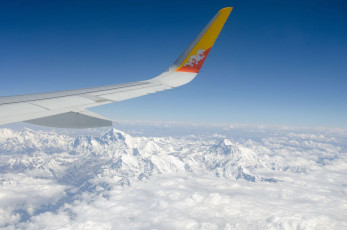 Die schneebedeckten Gipfel des mächtigen Himalaya-Gebirges sind teilweise von Wolken verdeckt. Dieses Bild wurde während eines Fluges von Delhi nach Paro aufgenommen.