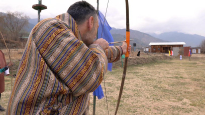 Ein Tourist versucht sich im Bogenschießen, dem Nationalsport Bhutans. In früheren Zeiten wurde der Bogen als Waffe verwendet, weshalb Pfeil und Bogen auf vielen alten Gemälden zu sehen sind