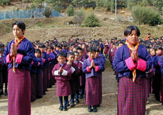 Schulkinder und ihre Lehrer versammeln sich zum Morgengebet in Bhutan. Sie alle tragen die traditionelle Kleidung von Bhutan © Beat Germann