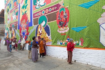 Bhutanische Gläubige in traditioneller Kleidung zollen dem riesigen Avalokitesvara, der auf der Utse (Hauptturm des Punakha Dzong) ausgestellt ist, während einer Geburtstagsfeier des vierten Königs Tribut. Während des Festes wird ein Symbol des Mitgefühls Buddhas, der Avalokitesvara, der in der Utse aufbewahrt wird, zur Schau gestellt. Der von Ngawang Namgyal Mitte des 17. Jahrhunderts erbaute Dzong ist eines der größten und majestätischsten Klöster Bhutans © Antonella865