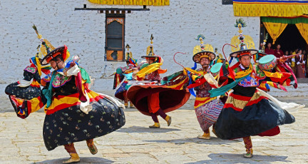 Mönche führen während des beliebten Paro Tsechu Festivals in Bhutan, dem Land des Donnerdrachens, religiöse Tänze auf. Die Feierlichkeiten finden im Paro Dzong statt, einem der eindrucksvollsten Anschauungsbeispiele für bhutanische Architektur © Samrat35