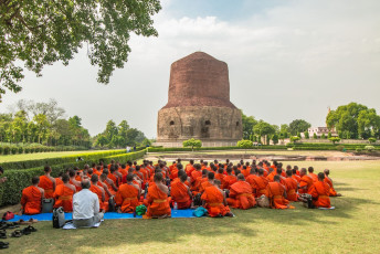 Buddhistische Mönche vor der massiven Dhamekh Stupa, wo Buddha seine erste Predigt an seine ersten fünf Schüler gehalten haben soll. Die Stupa wurde im Jahr 500 n. Chr. erbaut, um ein früheres Bauwerk zu ersetzen, das 250 v. Chr. von König Ashoka errichtet worden war. Sarnath, Varanasi © Ekkapob