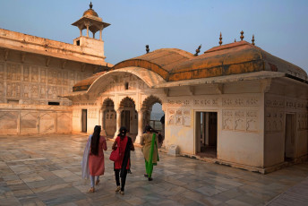 Drei einheimische Touristen vor dem Sheesh Mahal (Goldener Pavillon) im Roten Fort von Agra. Das interessant geschwungene Bangla-Dachkonstrukt ist wie das einer bengalischen Strohhütte geformt © akov Oskanov