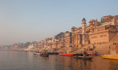 Touristen betrachten die eindrucksvollen Gebäude am Flussufer und die Sehenswürdigkeiten der heiligen Stadt Varanasi von einer Bootsfahrt auf dem Ganges aus - Foto von javarman