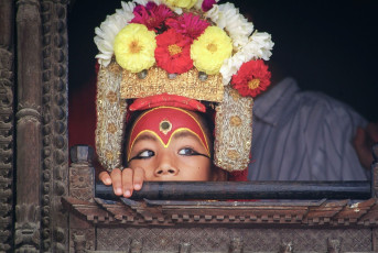 Die lebende Göttin, auch Kumari Devi genannt, blickt durch ein Fenster ihres Hauses im Kumari Ghar, einem Palast in Kathmandu. Diese jungen Mädchen gelten traditionell als Erscheinungsformen der Muttergöttin Taleju, der wichtigsten Beschützerin Nepals - Foto von Ron Ramtang