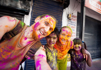 Holi ist ein farbenfrohes Fest, das allen gefällt, auch diesem europäischen Paar und diesen indischen Kindern mit farbigem Pulver in ihren Gesichtern und auf ihren Kleidern. © Pikoso.kz / Shutterstock