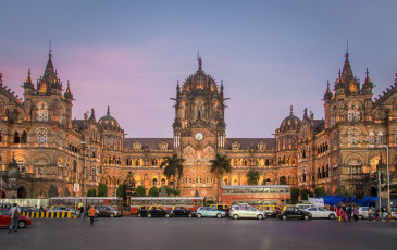 Der historische Chhatrapati Shivaji-Bahnhof in Mumbai wird von den Strahlen der untergehenden Sonne in einen goldenen Farbton getaucht. Er wurde im Stil der italienischen Gotik erbaut, gehört zum UNESCO-Weltkulturerbe und ist einer der meistfrequentierten Bahnhöfe Indiens.