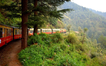 Fahrgäste können auf ihrer Reise die Berge und Täler sehen, wenn sie mit dem „Spielzeugzug“ von Shimla nach Solan, Indien, fahren. © snap_rsg/ Shutterstock