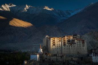 Anfang Oktober geht die Sonne über dem Leh Palast auf, mit der höchsten befahrbaren Straße über den Khardund La Pass im Hintergrund. Leh, Ladakh.