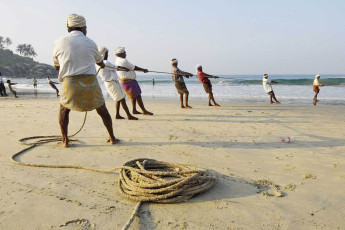 Fischer ziehen ihre Netze beim Kovalam Beach in Kerala aus dem Meer. Fischen ist noch immer die Haupteinkommensquelle der Einheimischen in ganz Kerala - Foto von Vlad Karavaev