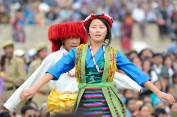 Junge Dorfbewohner in historischen tibetischen Kostümen führen einen Volkstanz auf. Letzter Tag des jährlichen Festes für das ladakhische Erbe in Leh, Indien – Foto von eAlisa