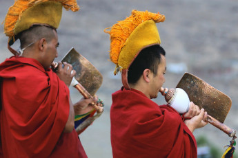 Buddhistische Mönche spielen während der Morgenzeremonie bei der Thiksey Gompa in Ladakh, Indien, rituelle Musik auf der tibetischen Trompetenschnecke – Foto von Tatiana Belova