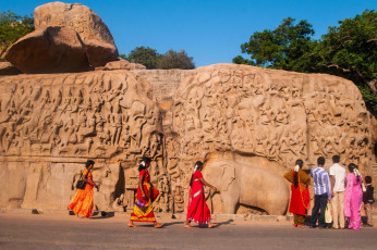 Besucher spazieren an einem riesigen Felsen in Mahabalipuram vorbei, dem Zentrum der antiken Felshauerei in Tamil Nadir, Südindien