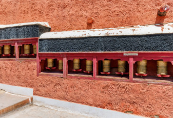 Verschiedene Reihen von Gebetsmühlen, die an den Wänden des Klosters Thiksey Gompa in Leh Ladakh befestigt sind © Vadim Petrakov