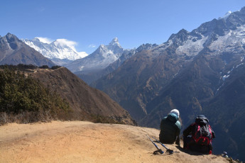 Ein paar Bergsteiger ruhen sich aus, um Luft zu holen und den herrlichen Blick auf den Mount Everest in der Ferne zu genießen, Khumjung © Alexander Jung