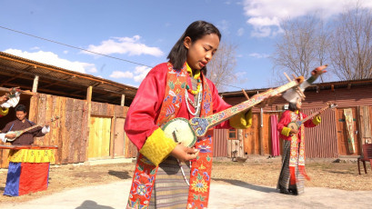 Junge Musiker treten während einer traditionellen bhutanischen Tanzshow in Paro, Bhutan, auf. Mit Musik und Tanz werden religiöse Geschichten erzählt und es wird geglaubt, dass die Anwesenden von ihren Sünden gereinigt werden © Alp Galip