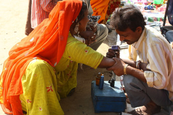 Eine Rajasthani-Frau, die ein Tattoo auf ihre Hand bekommt in Bhairongarh Village, Rajasthan, Indien