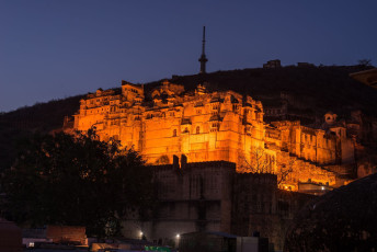 Leuchtendes Stadtbild bei Bundi in der Abenddämmerung. Das majestätische Fort thront über der Stadt. Bundi ist eine kleine malerische Stadt in Rajasthan, die für ihre alten Festungen, Paläste und kleinen Cafés berühmt ist