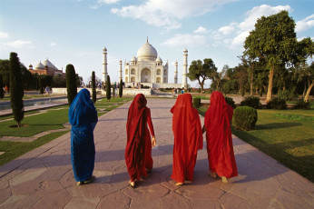 Inderinnen gehen auf das spektakuläre Taj Mahal zu, das von grünen Gärten umgeben ist, Agra, Uttar Pradesh, Indien © oversnap