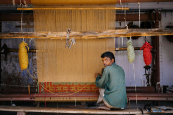 Ein Mann arbeitet an einem schönen Teppich an seinem kleinen Stand in den Straßen von Jaipur, Rajasthan, Indien © Costas Anton