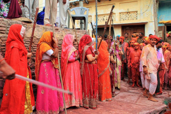 Frauen tragen lange Stöcke zum Schlagen der Männer als ein Ritual für die Lathmar Holi (Farbenfest) Feierlichkeiten in Nandgaon, Indien - Foto von AJP