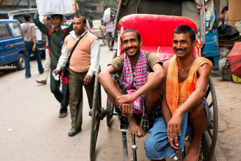 Zwei Arbeiter mit von Hand gezogener Rikscha lächeln während ihrer Pause auf der Straße. Der „Straßenraum“ in Kolkata beträgt nur 6%, in Delhi sind es im Vergleich dazu 23% und in Mumbai 17% – Foto von Radiokafka