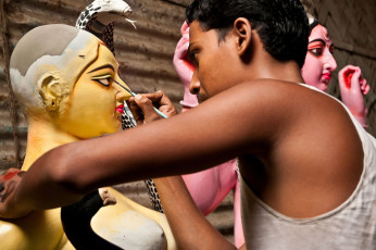 Ein Künstler malt das Auge einer Göttin am 14. August 2011 in Kumartuli, Kolkata, Indien. Diese Götterfiguren werden für das bengalische Fest Durga Puja, auch bekannt als Dassera, hergestellt – Foto von Neelsky