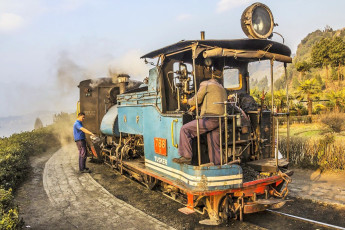 Die historische Schmalspurbahn von Darjeeling bei einem Zwischenstopp. Der Fahrer schmiert die Maschine mit Öl - Foto von Anandoart