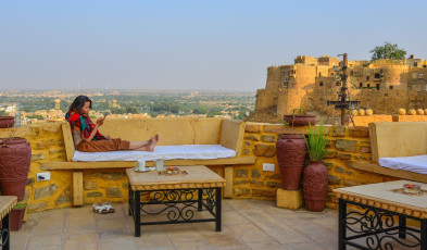 Ein ausländischer Tourist liest in einem Café im Fort von Jaisalmer, Rajasthan. Dieses gewaltige Fort überblickt die Weite der großen Wüste Thar und verfügt über vier riesige Tore, sieben Jain-Tempel, einen Königspalast und zahlreiche Handelshavelis.