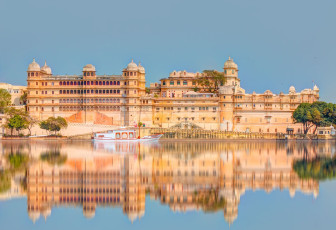 Der prächtige Stadtpalast von Udaipur spiegelt sich im Wasser des Pichola-Sees. Dieser große Palastkomplex wurde über einen Zeitraum von 400 Jahren erbaut, wobei jeder Herrscher zusätzliche Strukturen wie Mahals, Höfe, Pavillons, hängende Gärten und vieles mehr hinzufügte
