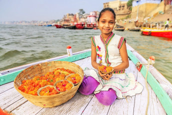 Kleines Mädchen verkauft Blumenkerzen im Boot, Fluss Ganges, Varanasi - Foto von Bartosz Hadyniak