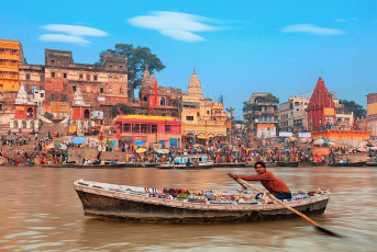 Eine Ansicht der heiligen Ghats von Varanasi mit einem fahrenden Boot - Foto von Lena Sarditova