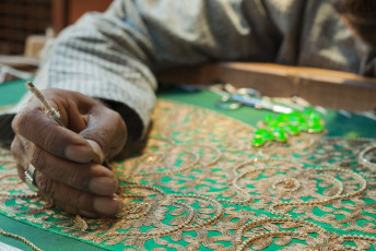 Ein Kunsthandwerker bestickt Kleidung auf traditionell indische Weise mit goldenem Faden, Zardosi-Stickerei von Agra - Foto von PI