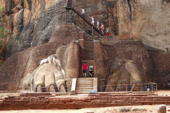 Besucher steigen, dicht vorbei an den Klauen, die Stufen hinauf zum einzigen Teil des Löwenfelsentorweges von Sigiriya, der den Lauf der Zeit überstanden hat. Diese historische Felsenfestung gehört zum UNESCO-Weltkulturerbe © slava296