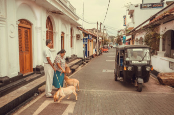 Ein einheimisches Paar schlendert mit seinem Hund an einem Tuk-Tuk in der alten Festungsstadt Galle entlang, Sri Lanka © Radiokukka