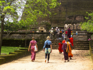Junge Mönche in ihren unvergleichlichen, farbenfrohen Gewändern mit Besuchern in den Ruinen von Polonnaruwa. Hier wurde einst das zweitälteste Königreich Sri Lankas gegründet © DavorLovinic