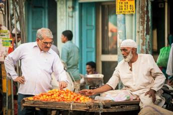 Indischer Mann kauft auf den Straßen von Alt Delhi Tomaten bei einem muslimischen Händler - Foto von Elena Ermakova