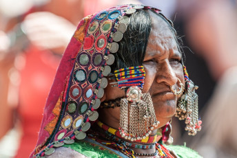 Ein wunderschönes Porträt einer Lamani-Frau mit Ornamenten in traditioneller Kleidung  auf dem bekannten Anjuna-Flohmarkt von Nord-Goa © AndreaObzerova