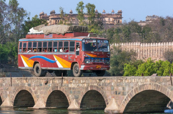 Der Bus überquert eine Brücke über dem Fluss Betwa, Raja-Palast im Hintergrund, Orchha - Foto von Claudine Van Massenhove