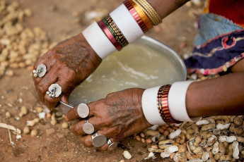 Die Hand einer Lambadi-/Banjara-Frau ist mit Schmuck aus Münzen geschmückt. Sie wäscht ihren Teller nach dem Essen – Foto von vdhya