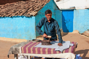 Ein Mann bügelt die Wäsche mit einem altem Bügeleisen - Foto von Radiokafka