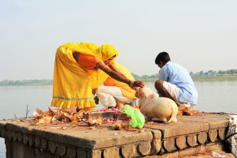 Menschen vollziehen die Morgenpooja an den Ghats des heiligen Flusses Narmada in Maheshwar, Indien. Für Hindus ist der Narmada einer der 5 heiligen Flüsse Indiens – Foto von Stefano Ember