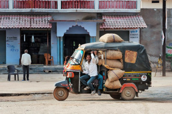 Mit Säcken beladene indische Rikscha mit Fahrer auf der Straße, Orchha – Foto von Elena Mirage