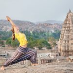 Eine Frau beim Yoga auf einem Felsen im Virupaksha-Tempel in Karnataka