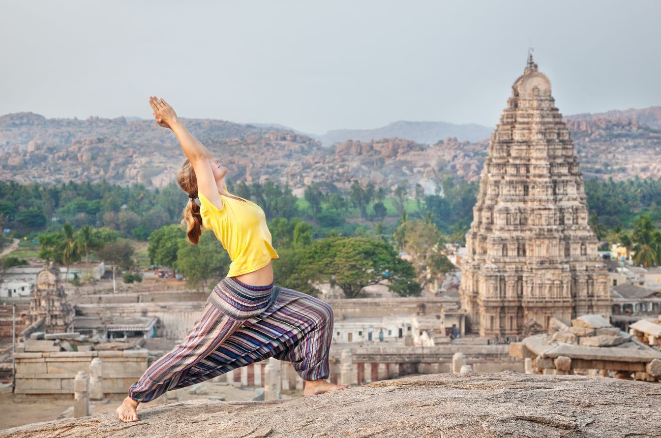 Eine Frau beim Yoga auf einem Felsen im Virupaksha-Tempel in Karnataka